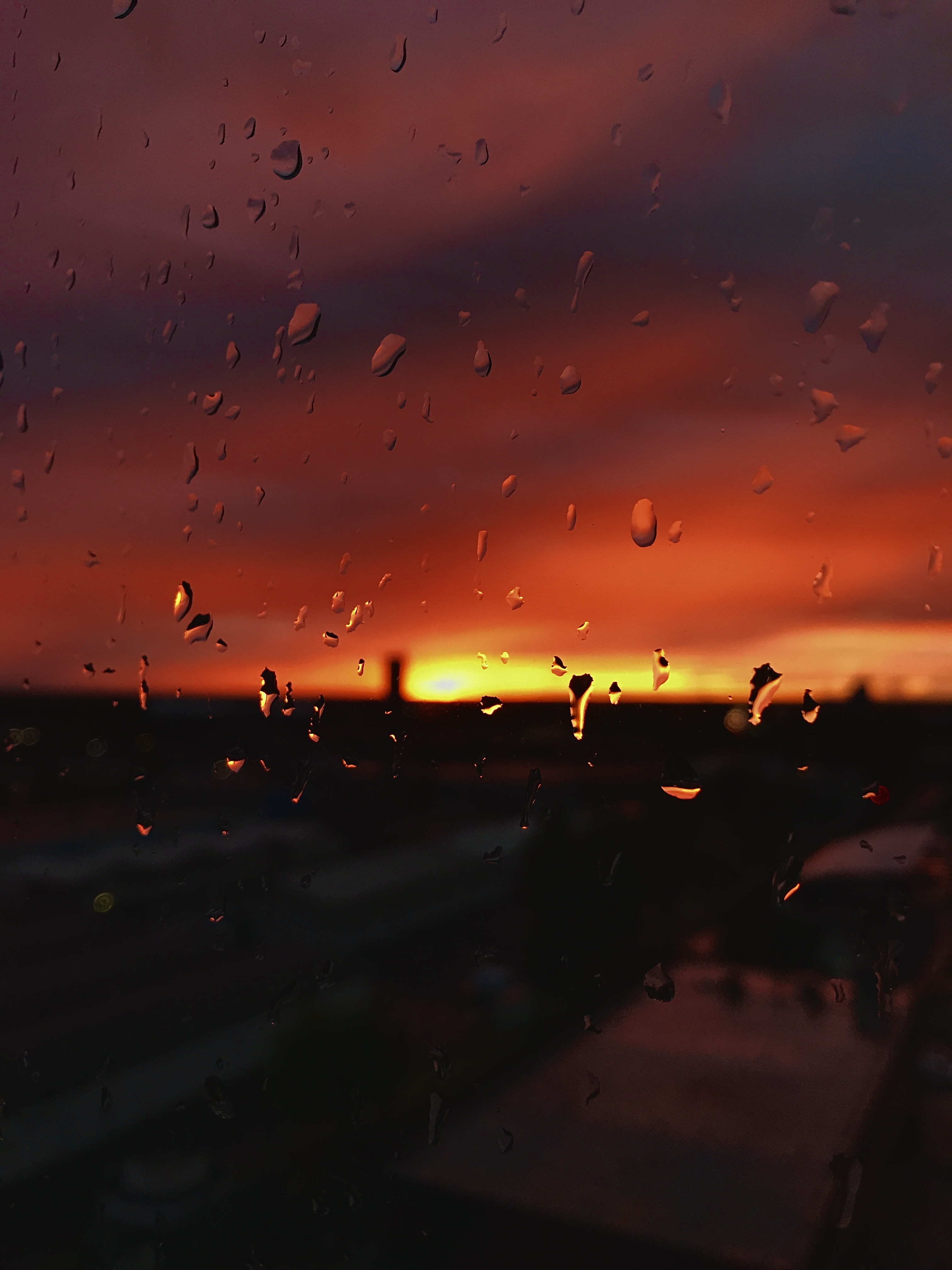 Ablakon pompázó vízcseppek, a vihar utáni naplementében